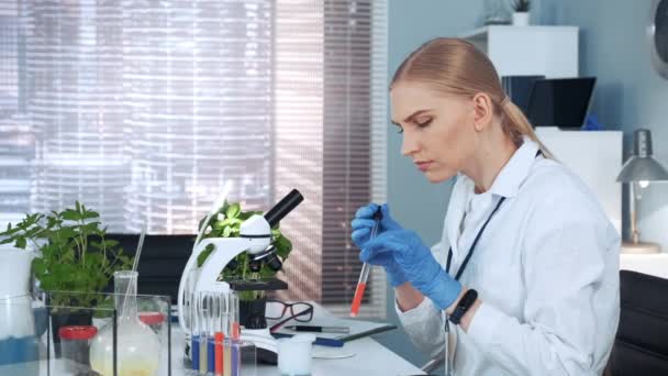 Kadın araştırmacı bilim adamı mikroskop slaytına örnek bırakıyor ve inceliyor. — Stok video