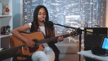 Ev stüdyosunda şarkı kaydeden ve gitar çalan zenci bir kadın vokalist.