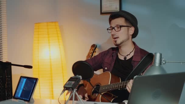 Alegre joven músico tocando la guitarra y cantando en el micrófono en el estudio en casa — Vídeos de Stock