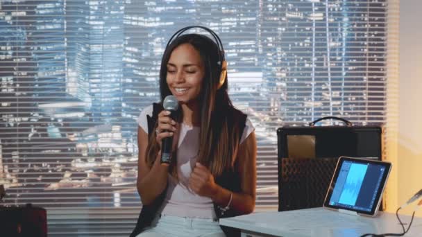 Elegante chica de raza mixta cantando en el micrófono en el ensayo en el estudio en casa — Vídeos de Stock