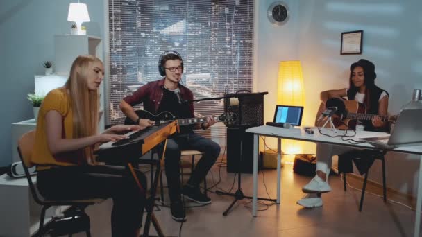 Hudební skupina mladých smíšených lidí nahrává novou skladbu v domácím studiu