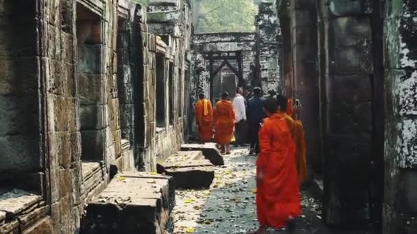 Mladí buddhističtí mniši kráčející v chrámu v šafránových šatech a vyhlížející přes Angkor Wat. 4K — Stock video