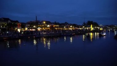 Yüzen fenerler ve teknelerle gece nehri manzarası. Hoi An, Vietnam 4K