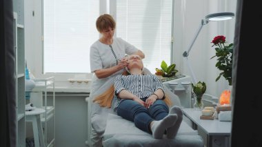 Sarışın kadın güzellik salonunda mikro dermabrüksiyon yaptırıyor.