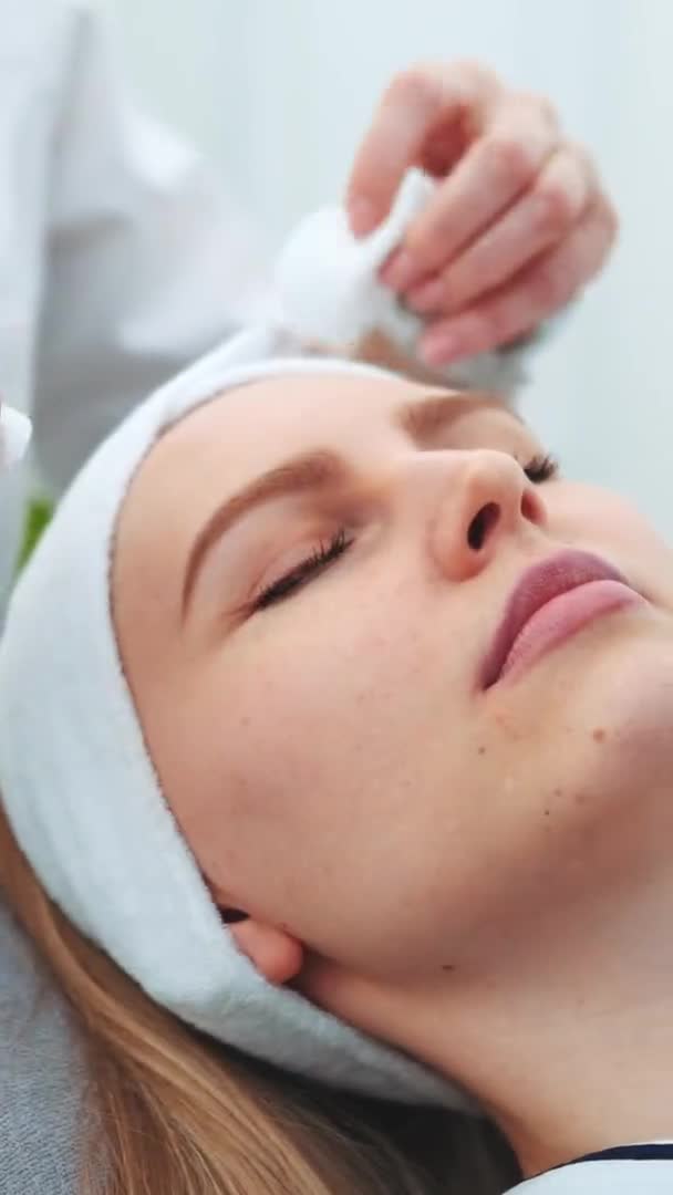 美容師は綿のパッドで女性の顔を拭く — ストック動画