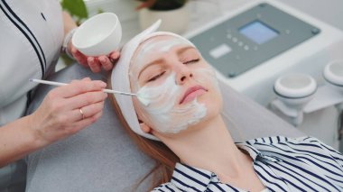 Güzellik uzmanının güzellik salonunda kadınların yüzüne krem maske taktığı orta boy bir fotoğraf.
