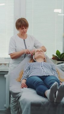 Sarışın genç bir kadın güzellik salonunda yüz masajı yaptırıyor.