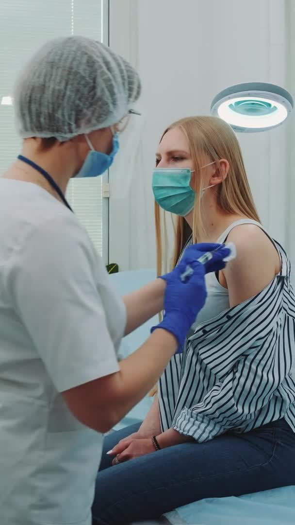 Kvinnlig läkare i medicinska skyddsdukar som injicerar i kvinnor beväpnar ett vaccin mot coronavirus — Stockvideo