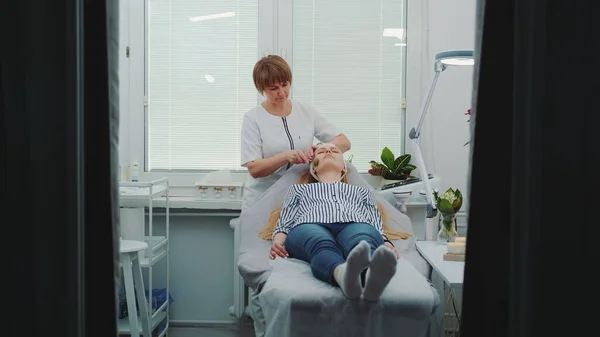 Sarışın genç bir kadın güzellik salonunda yüz masajı yaptırıyor.
