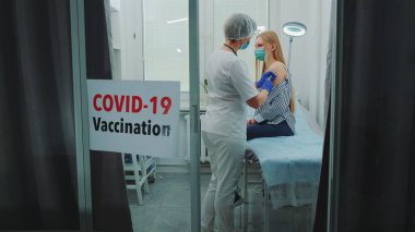 Kadın doktor bölge hastanesinde koronavirüse karşı aşı yapıyor.