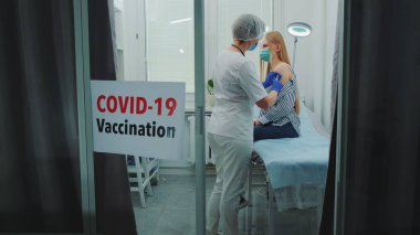 Kadın doktor bölge hastanesinde koronavirüse karşı aşı yapıyor.