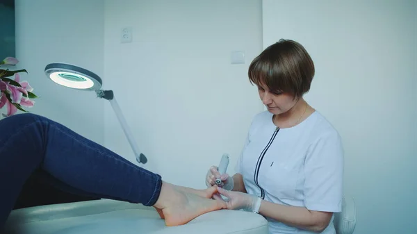 Vrolijke manicure het maken van een hardware pedicure voor vrouw. — Stockfoto