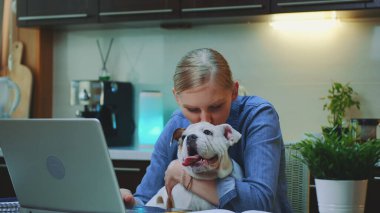 Mutfakta küçük köpeğe sarılan neşeli kadının yakın plan fotoğrafı.