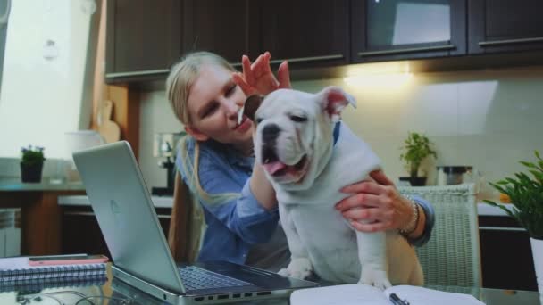 Loira menina de estimação bulldog e falando com ele na cozinha em casa — Vídeo de Stock
