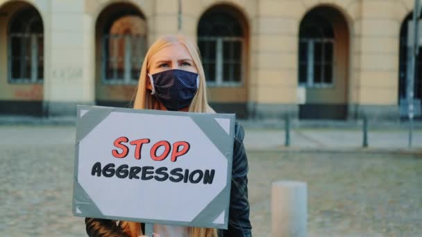 Protestpromenad: kvinna i skyddsmask protesterar för att stoppa aggression genom att hålla ångaren — Stockvideo