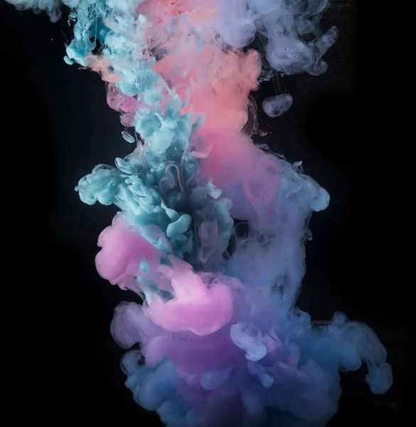 Colorful rainbow paint drops from above mixing in water. Ink swirling underwater.
