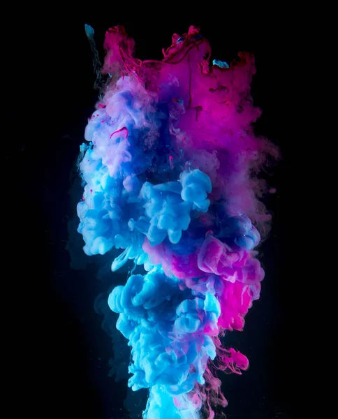 Colorful rainbow paint drops from above mixing in water. Ink swirling underwater.