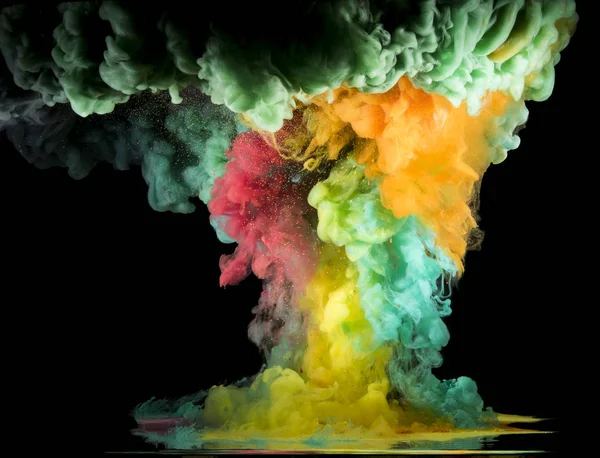 Colorful rainbow paint drops from above mixing in water. Ink swirling underwater