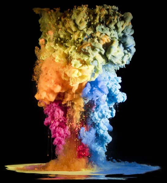 Colorful rainbow paint drops from above mixing in water. Ink swirling underwater