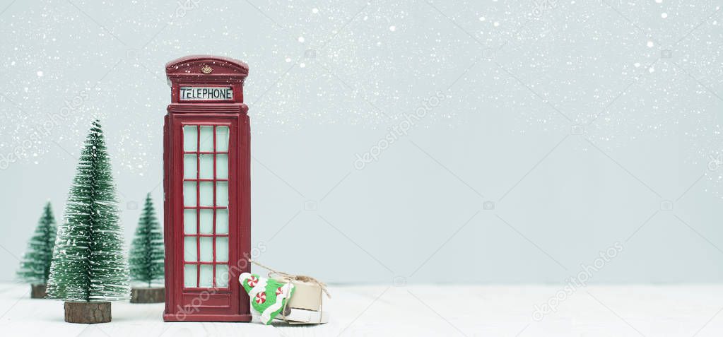 Banner with christmas decorations, toy red phone booth, trees, gifts on light background