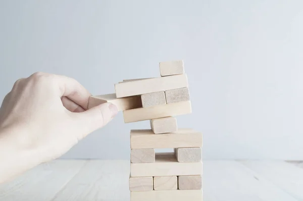 Menselijke hand houten baksteen trekken vanaf de toren — Stockfoto