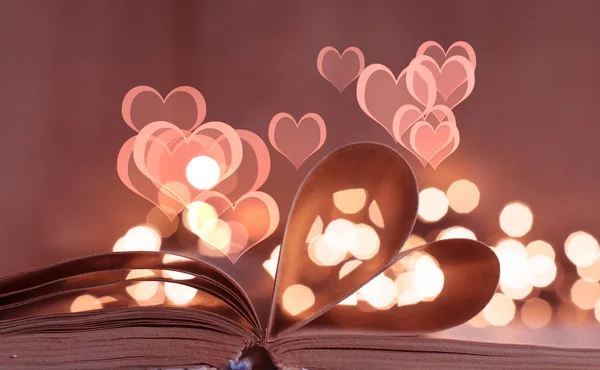 一本打开的书 以心脏的形状弯曲书页 以波克光为背景 — 图库照片