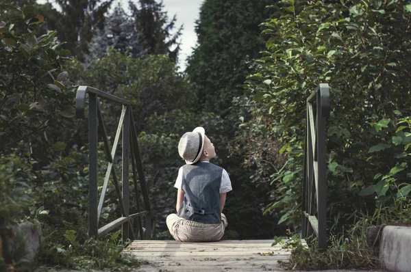 Kid sitting alone on a stairs in th garden — Stock Photo, Image