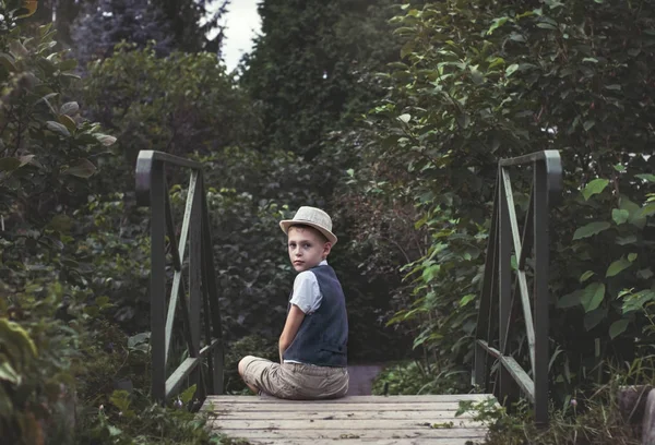 Kid sitting alone on a stairs in th garden — Stock Photo, Image
