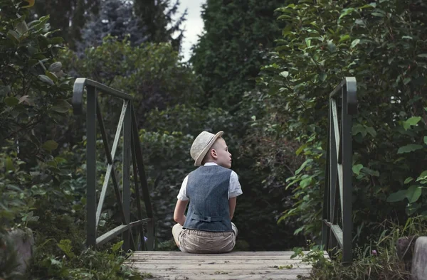 Kid sitting alone on a stairs in th garden — Stock Photo, Image