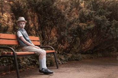 bir sonbahar parkında bankta oturan çocuk