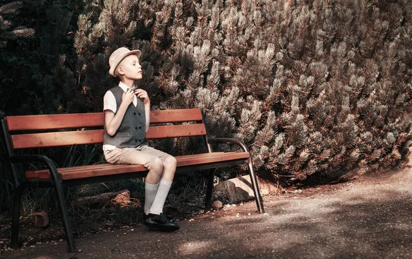 Child sitting at  the bench in a fall park — Stock Photo, Image