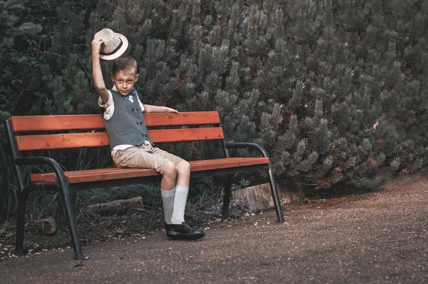 Ребенок сидит на скамейке в осеннем парке — стоковое фото