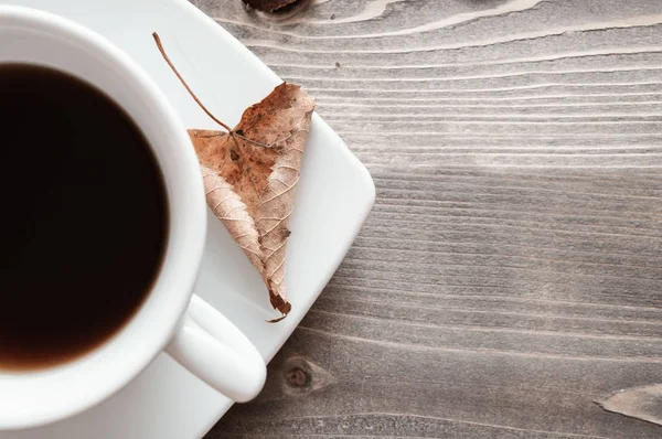 Kopje zwarte koffie en droog blad — Stockfoto