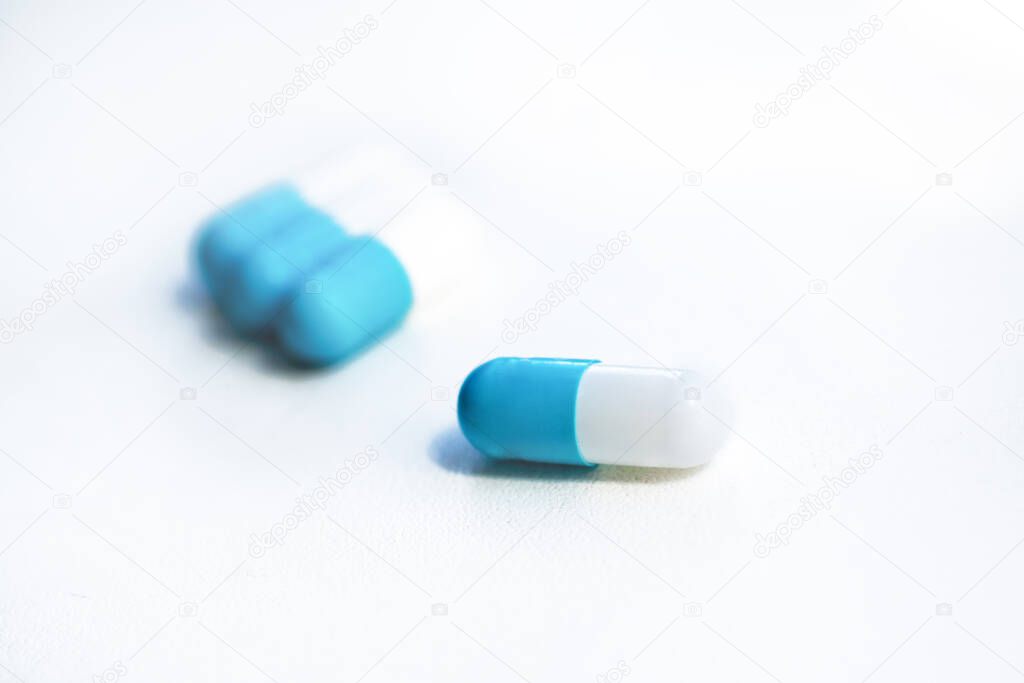 several blue capsules close-up on a white textured background