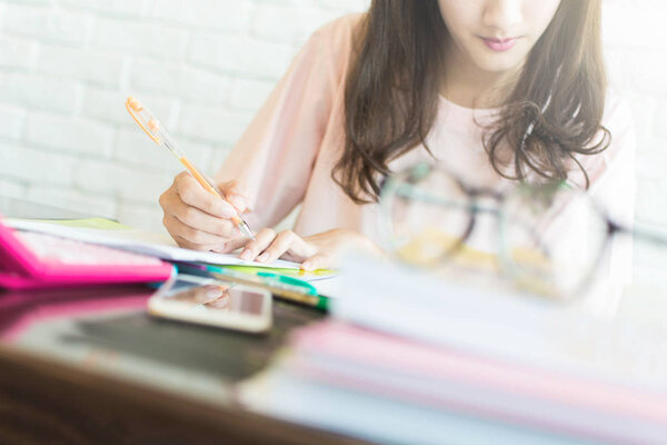 Asian Woman are recording family expenditures for a plan to spend the future in earnest, selective focus of hand ,family and financial concept.