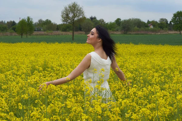 Sarı bir çiçek tarlasında bir kız, güzel bir bahar manzarası, parlak güneşli bir gün, kanola. Harika.