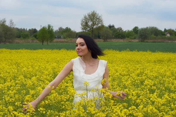 Sarı bir çiçek tarlasında bir kız, güzel bir bahar manzarası, parlak güneşli bir gün, kanola. Harika.