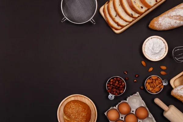 Homemade breads or bun, croissant and bakery ingredients, flour, almond nuts, hazelnuts, eggs on dark background, Bakery background frame, Cooking breakfast concept. Flat lay, Top view and copy space