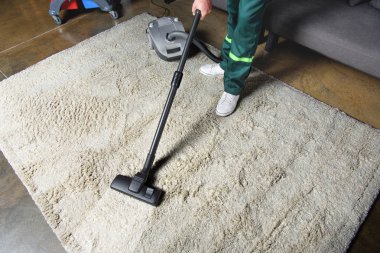 high angle view of man using vacuum cleaner and cleaning white carpet clipart