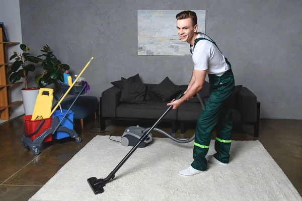 Knappe Jonge Man Schoonmaak Wit Tapijt Met Stofzuiger Lachend Camera — Stockfoto