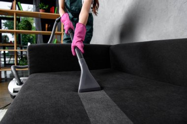 partial view of woman in rubber gloves cleaning furniture with vacuum cleaner   clipart