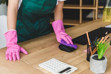 cropped shot of woman in rubber gloves cleaning office table clipart