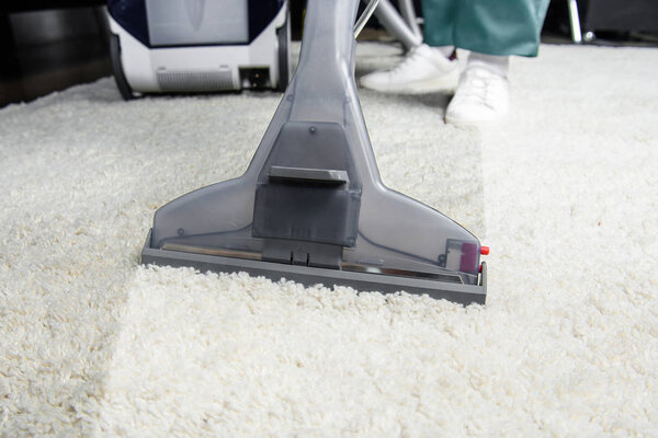 cropped shot of person cleaning white carpet with professional vacuum cleaner 