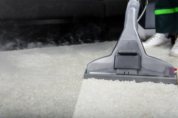 close-up view of person cleaning white carpet with professional vacuum cleaner 