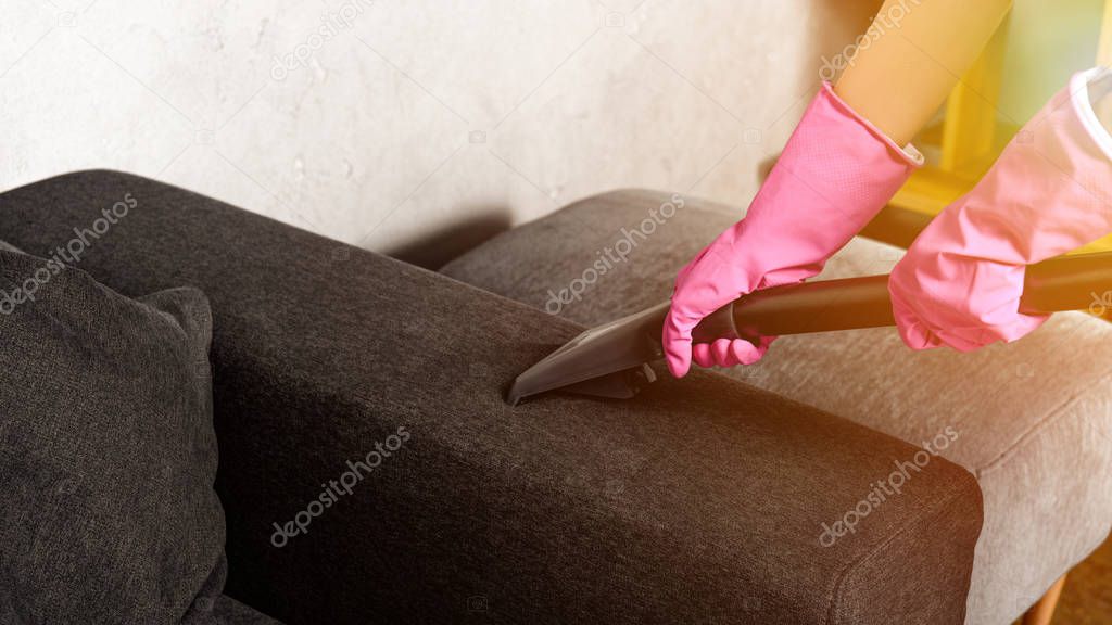 close-up partial view of person in rubber gloves cleaning furniture with vacuum cleaner 