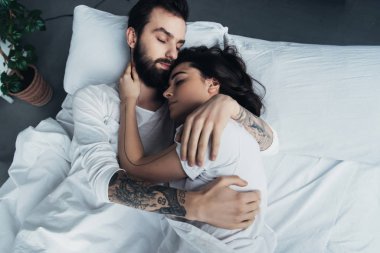 güzel genç çift yatakta uyurken kucaklayan dövme