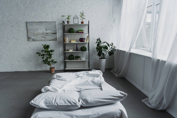 modern interior design of bedroom with rack, plants, bed, brick wall and copy space