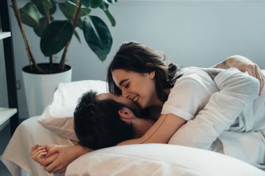 güzel genç gülümseyen iki kucaklayan ve evde yatakta yatan süre öpüşme