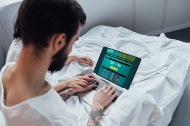 arkadan görünüşü yatakta yatarken, el ele tutuşarak ve ekranda sportsbet Web sitesi ile dizüstü bilgisayar kullanarak bir çift 