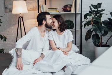 yakışıklı adam burun gülümseyen kadın evde yatakta ısırma sakallı